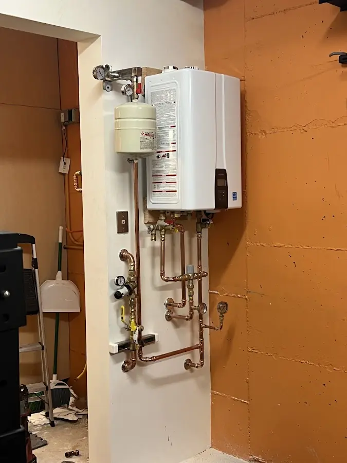 Plumbing technician inspecting water heater connections in Perry